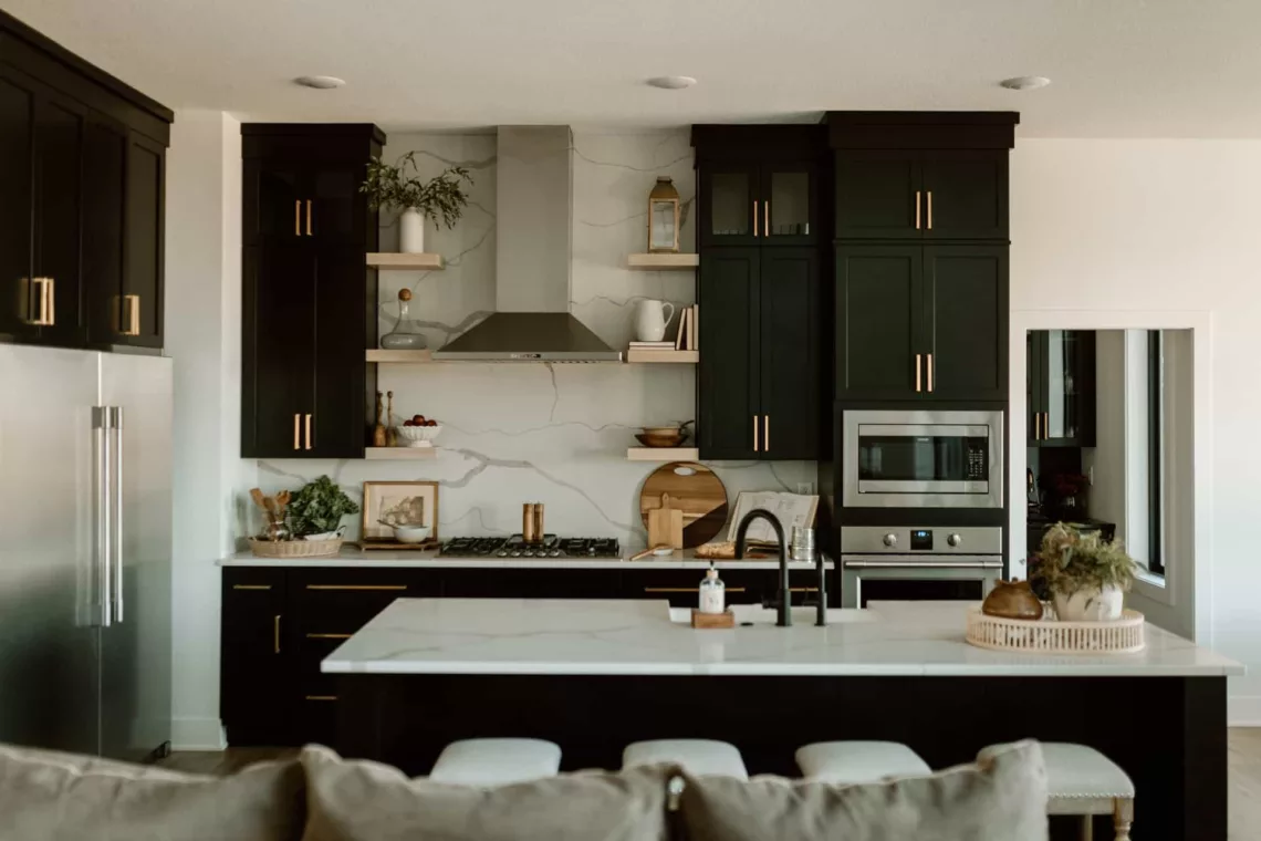custom built kitchen with white marble counters, black cabinets and stainless appliances
