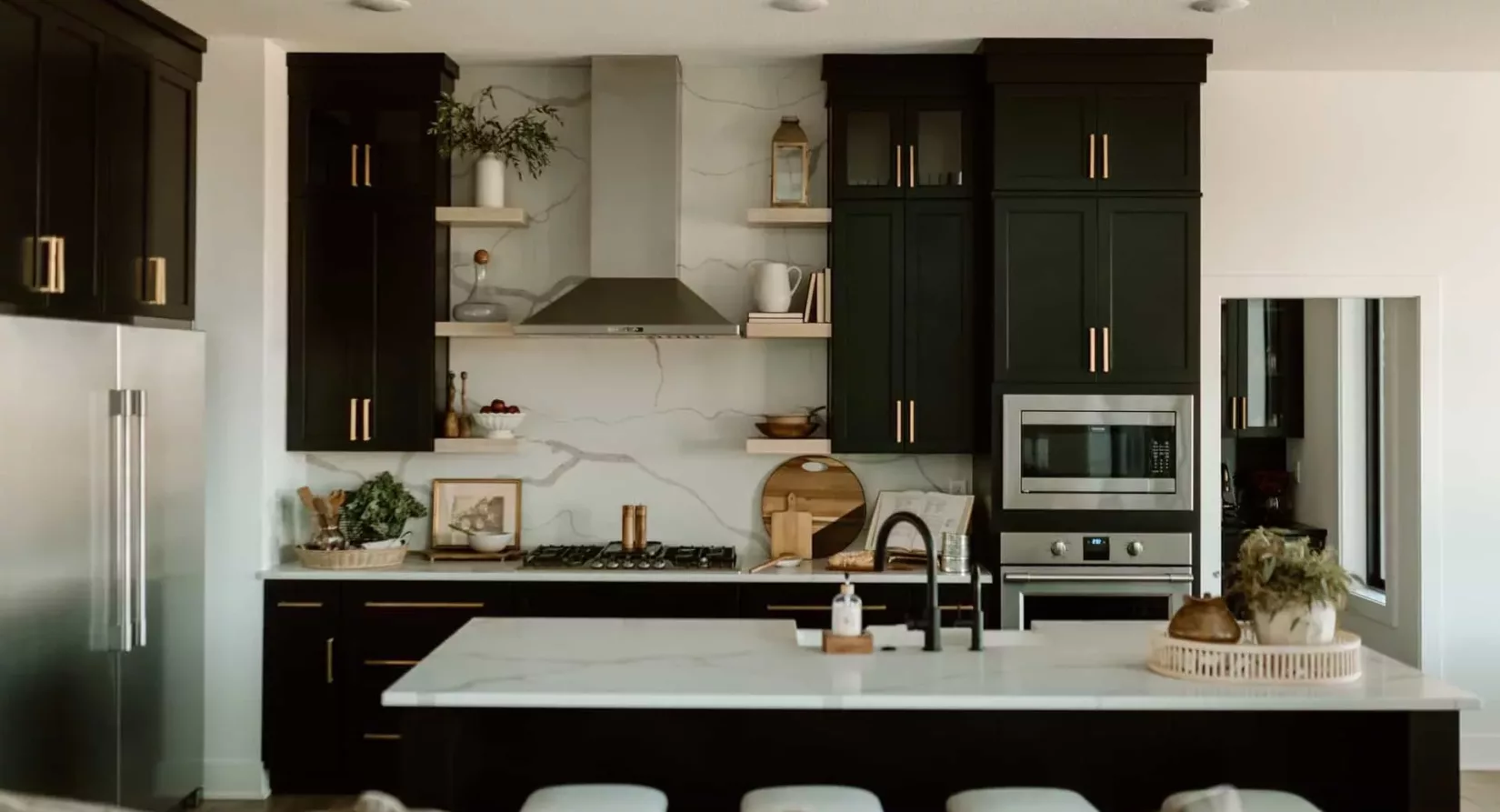 custom built kitchen with white marble counters, black cabinets and stainless appliances