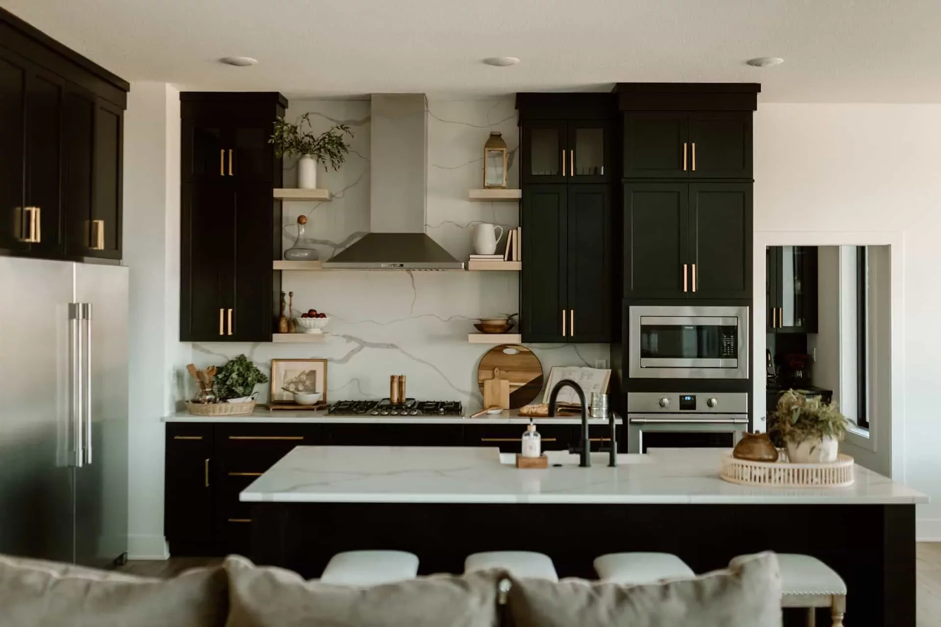 custom built kitchen with white marble counters, black cabinets and stainless appliances
