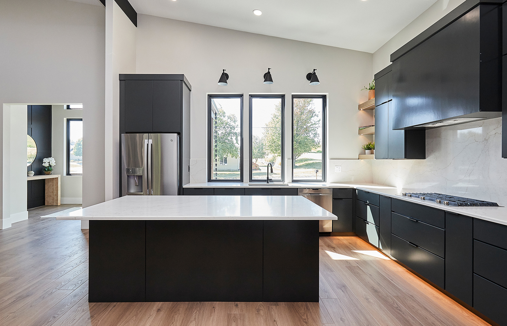 kitchen with white countertops, black cabinets and light plank flooring