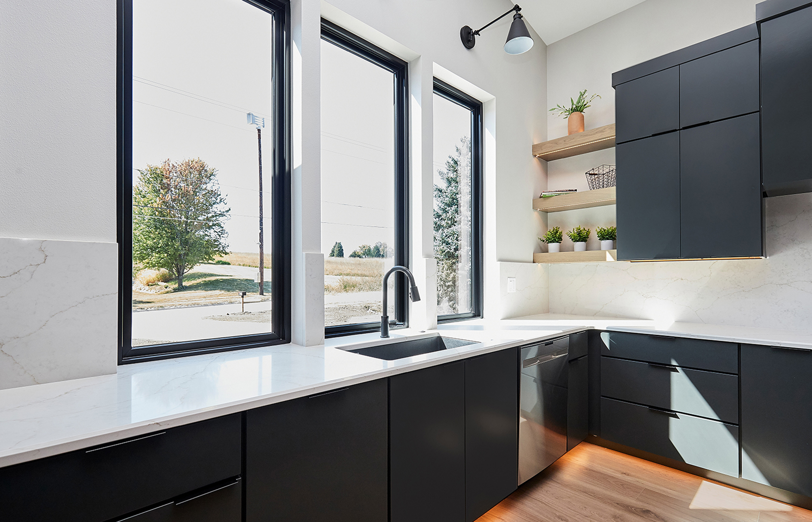 kitchen sink with black cabinets, white counters and tall windows