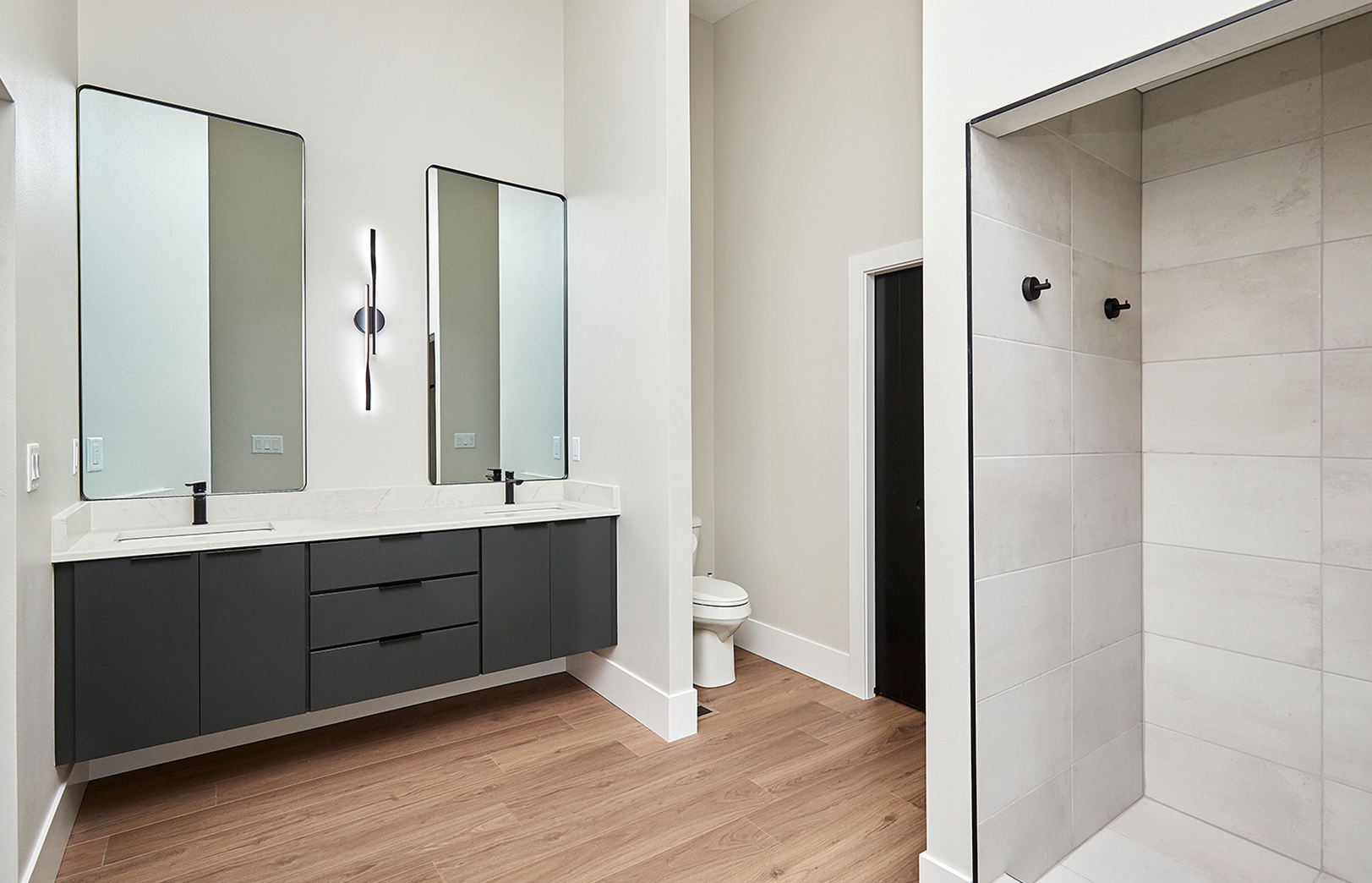 large new bathroom with two vanities, tall mirrors and shower with white tile
