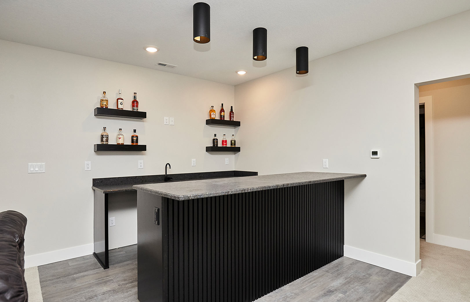 custom basement bar with shelves of liquor bottles