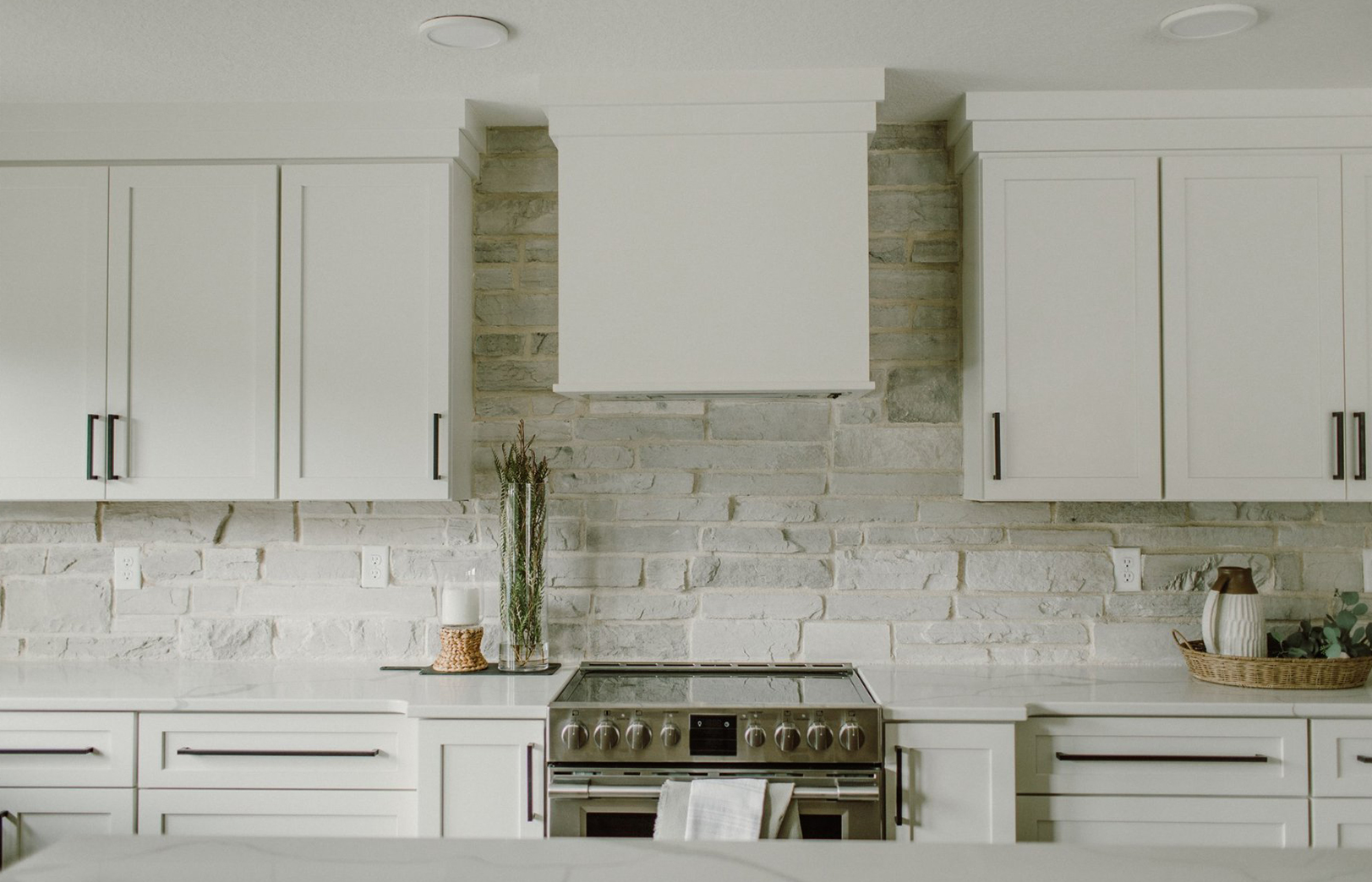 White kitchen cabinets around white stone kitchen at the stove