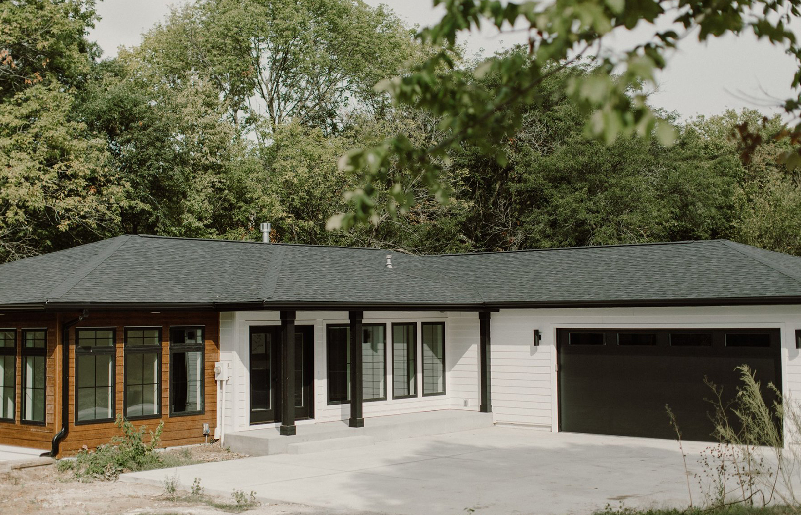 Exterior with white siding, black garage and roof and wood siding accent