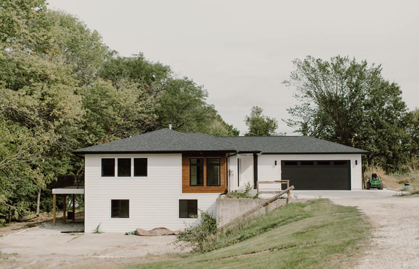 Exterior with white siding, black garage and roof and wood siding accent