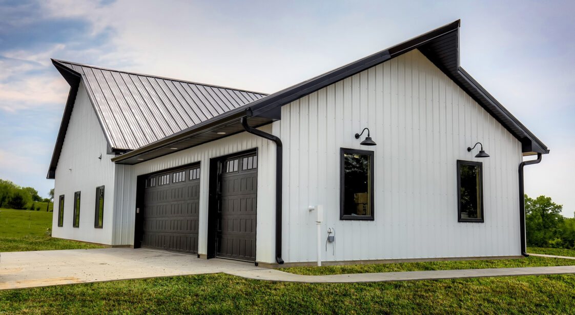 Exterior metal white home with black roof and black garage doors