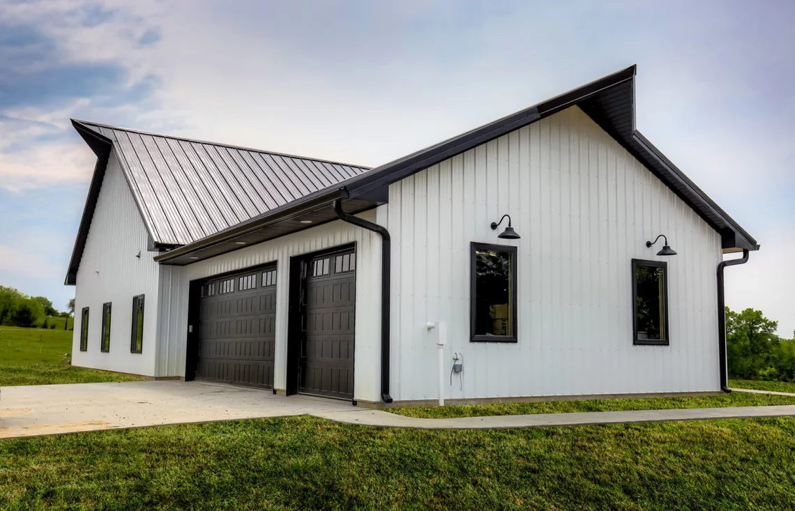 Exterior metal white home with black roof and black garage doors