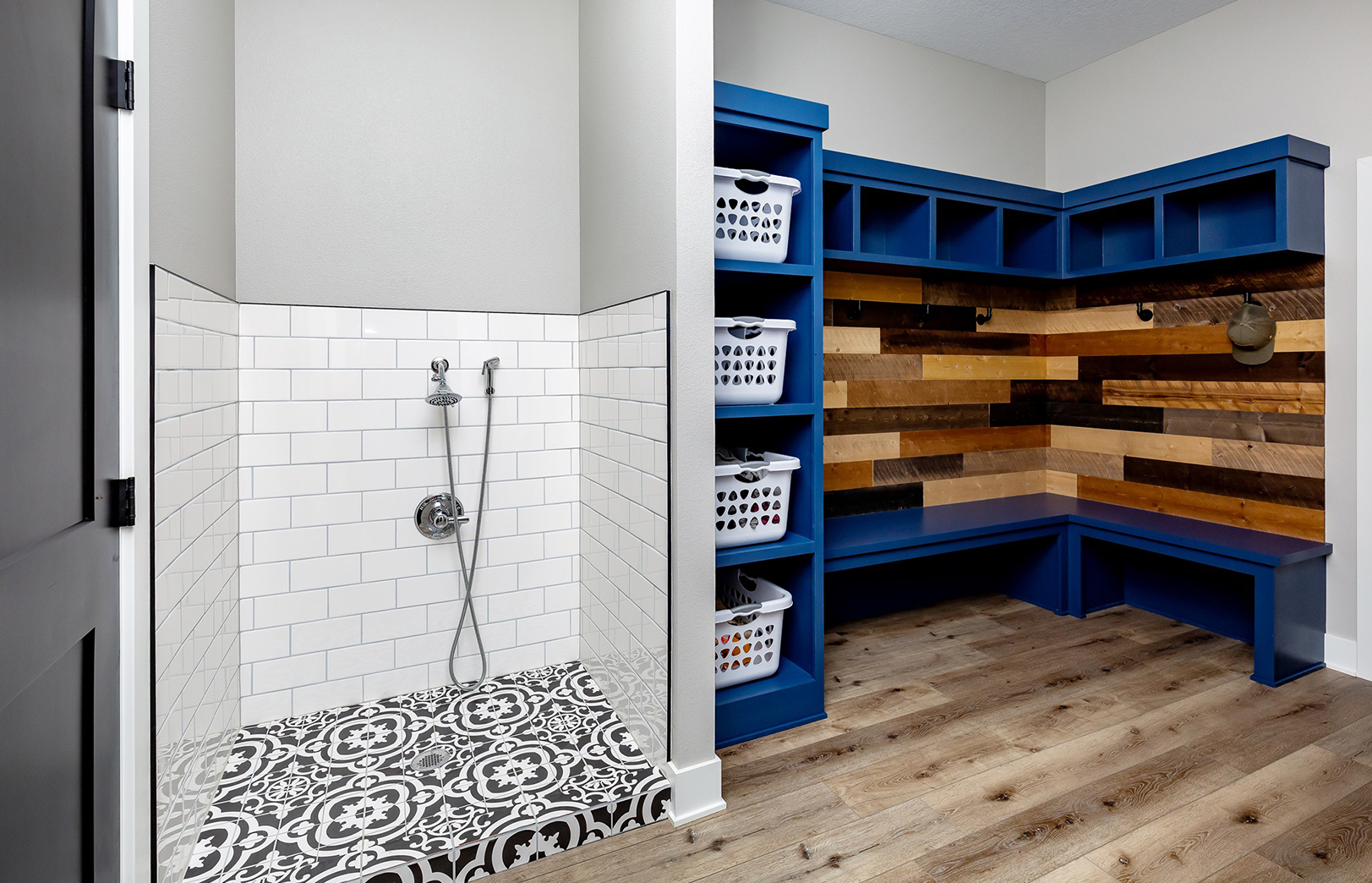 White tile dog shower in mudroom with blue cabinetry and wood accent wall