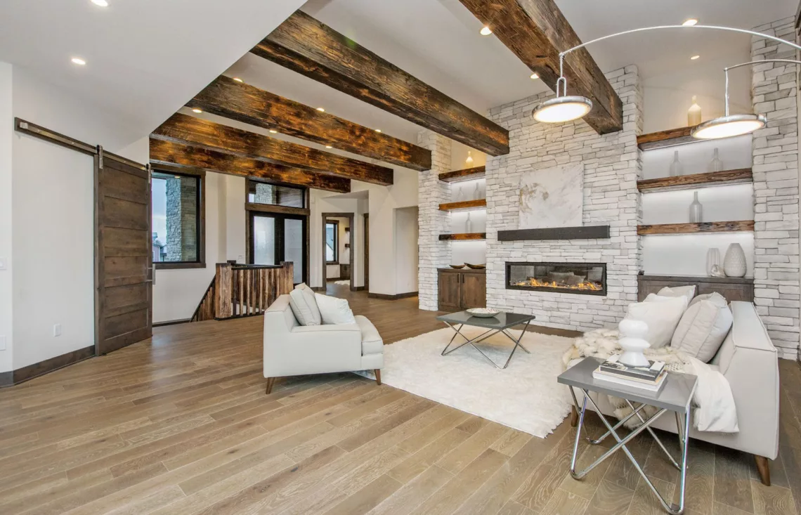 open living space with large beams and stacked stone fireplace