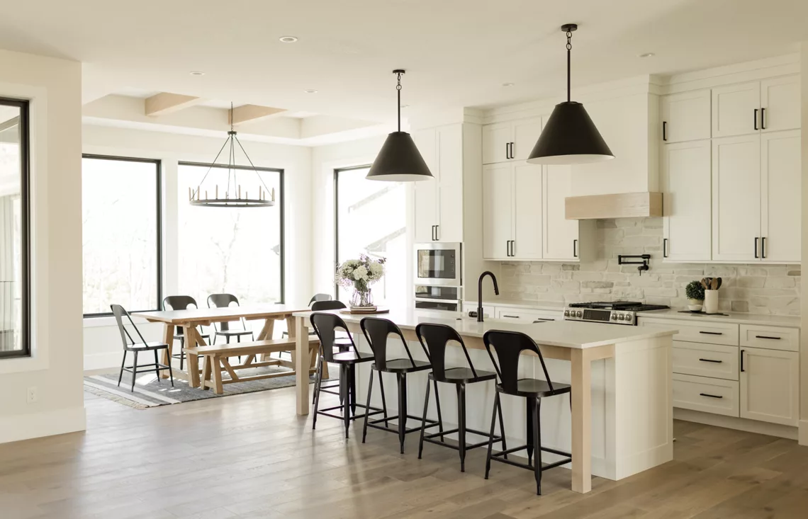 open concept eat-in kitchen with windows surrounding, white countertop and black fixtures