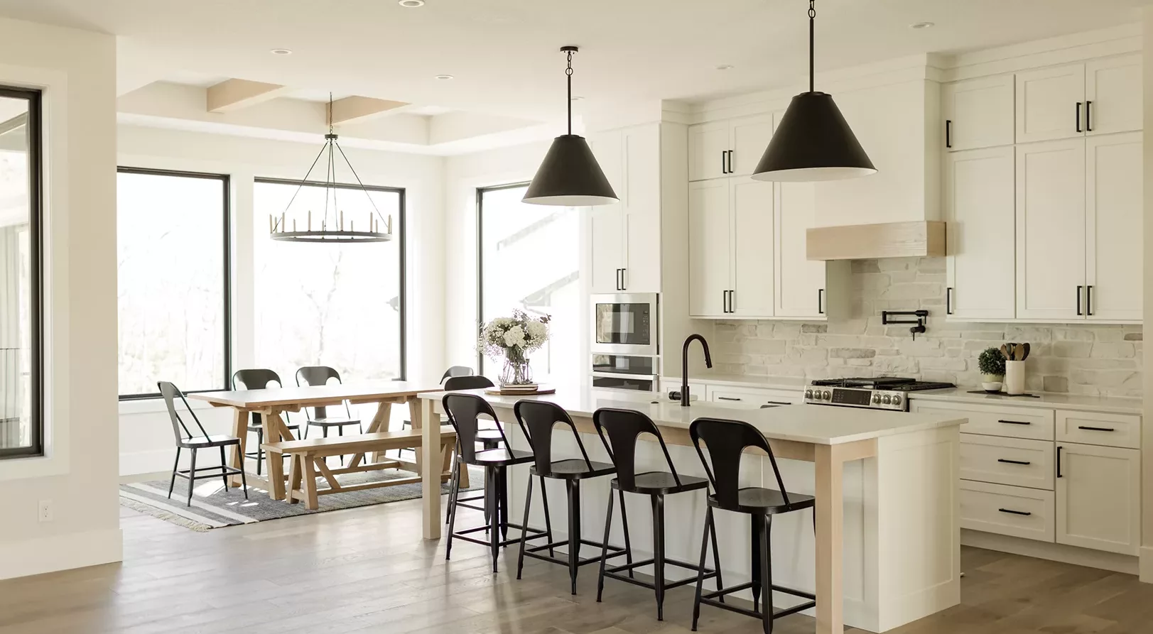 open concept eat-in kitchen with windows surrounding, white countertop and black fixtures