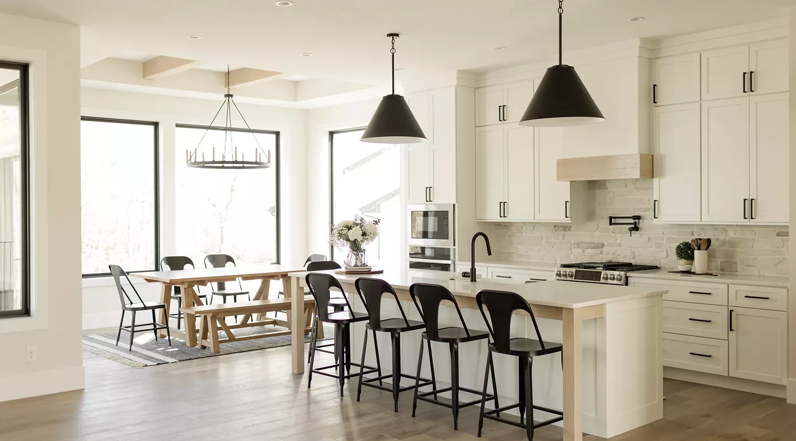 open concept eat-in kitchen with windows surrounding, white countertop and black fixtures
