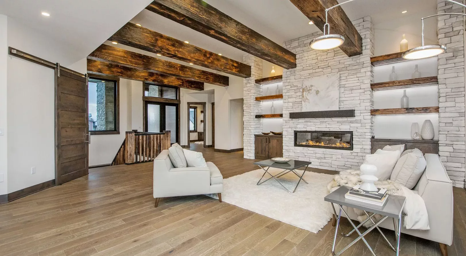 open living space with large beams and stacked stone fireplace