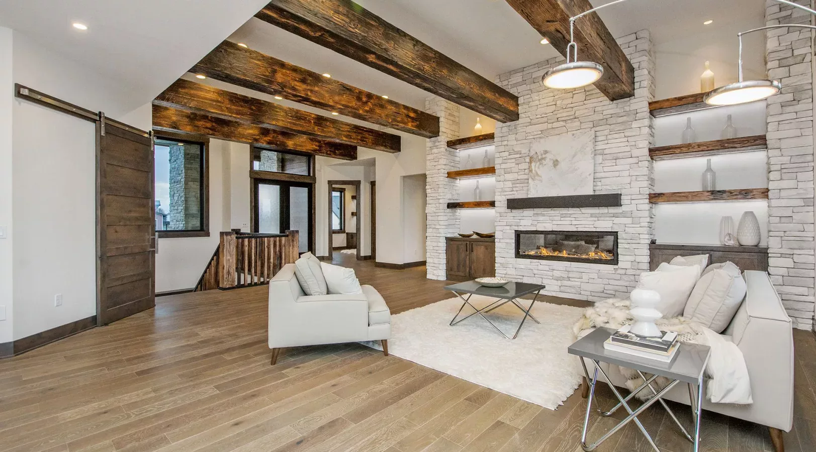 open living space with large beams and stacked stone fireplace