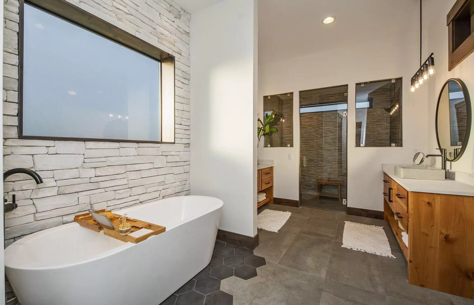 bathroom with stacked stone wall, soaking sub, custom tile and double walk-in shower