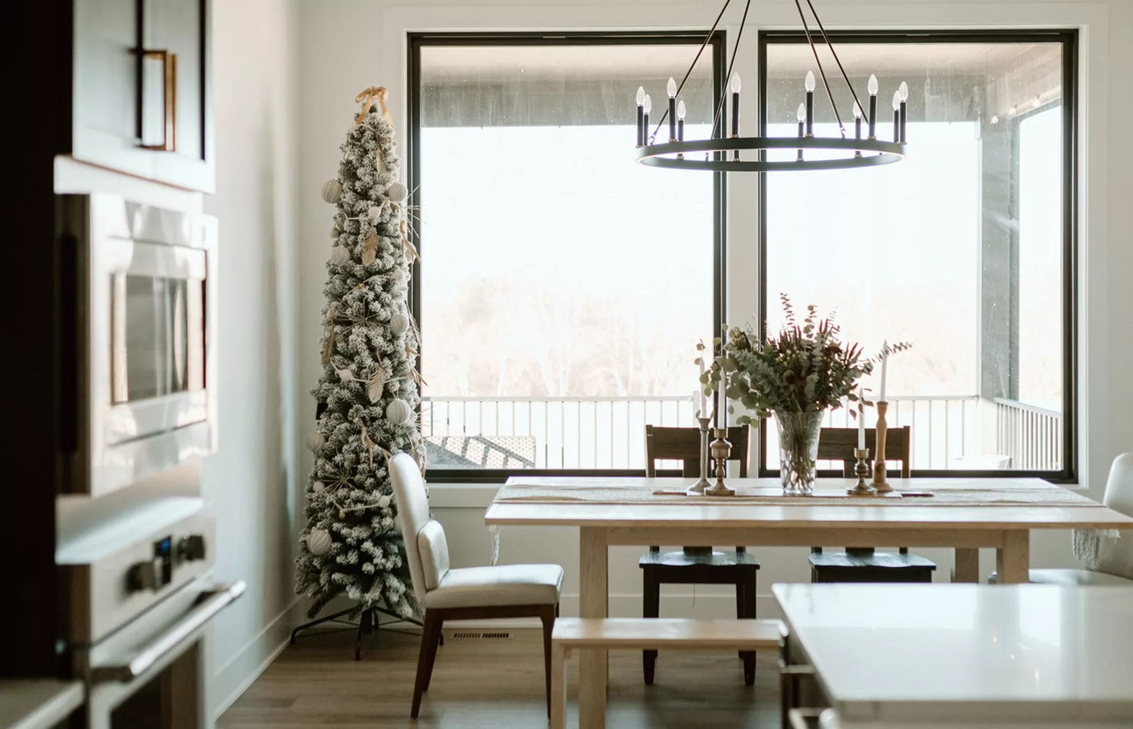 large windows behind dining area with large light fixture and table set with decorations