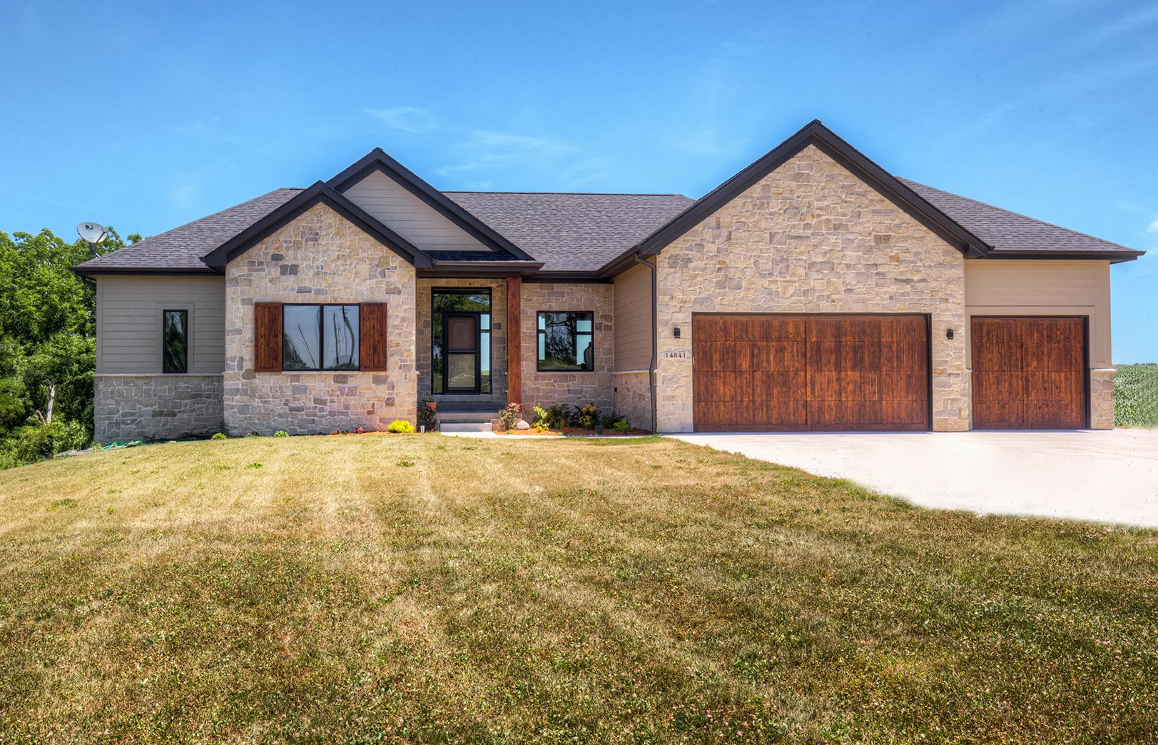 front of home with stacked stone front and rustic wood garage doors