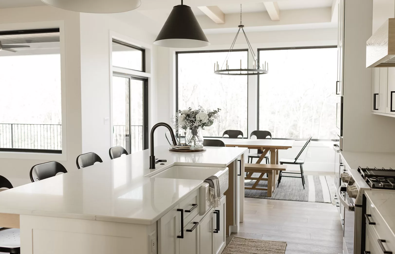 open concept eat-in kitchen with windows surrounding, white countertop and black fixtures