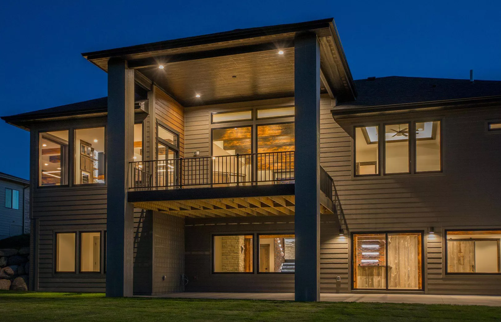 back exterior of home lit at night with patio and covered porch
