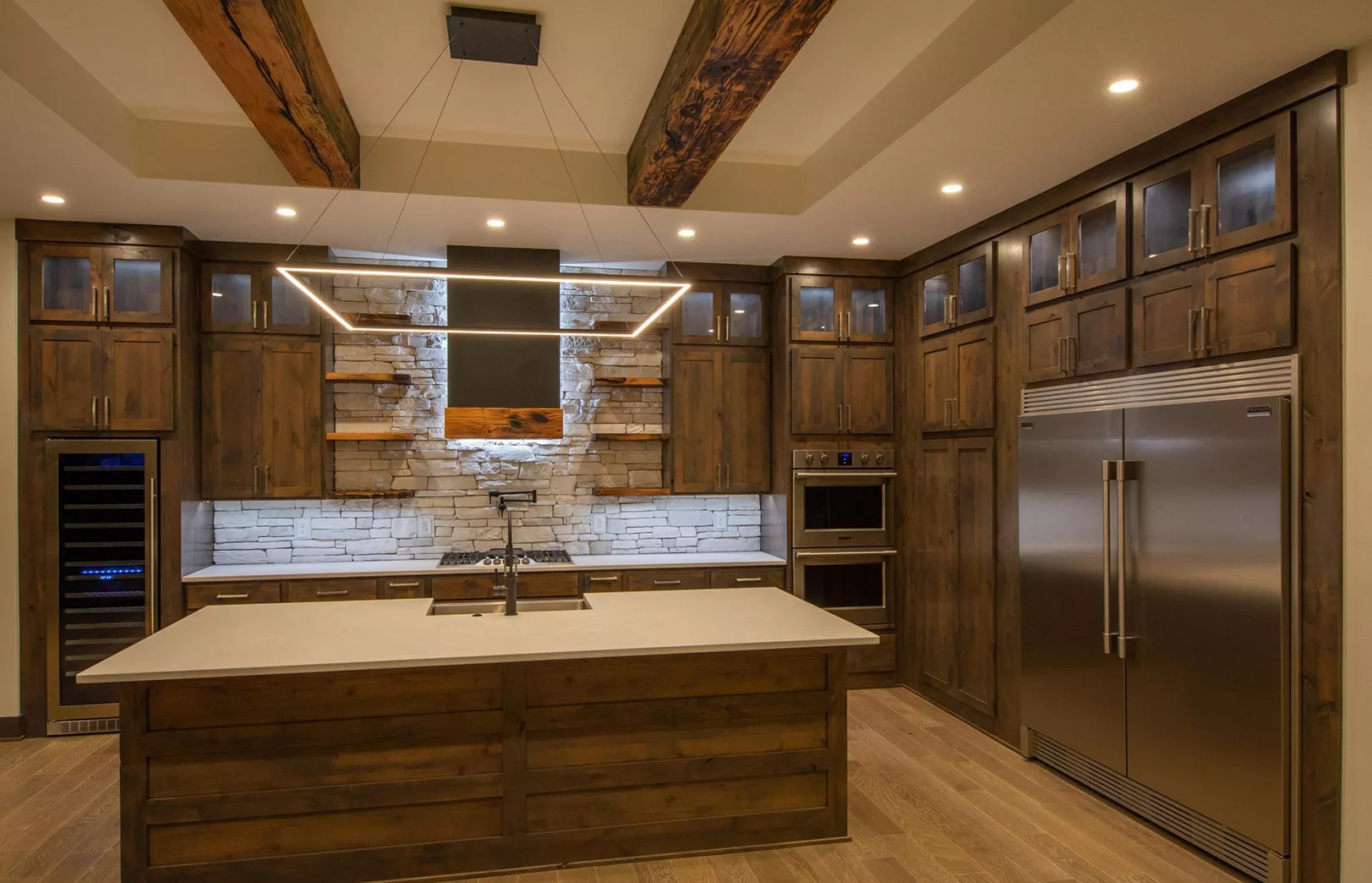 open eat-in kitchen with large wooden beams and dark stained wood cabinets, contemporary hanging light fixture
