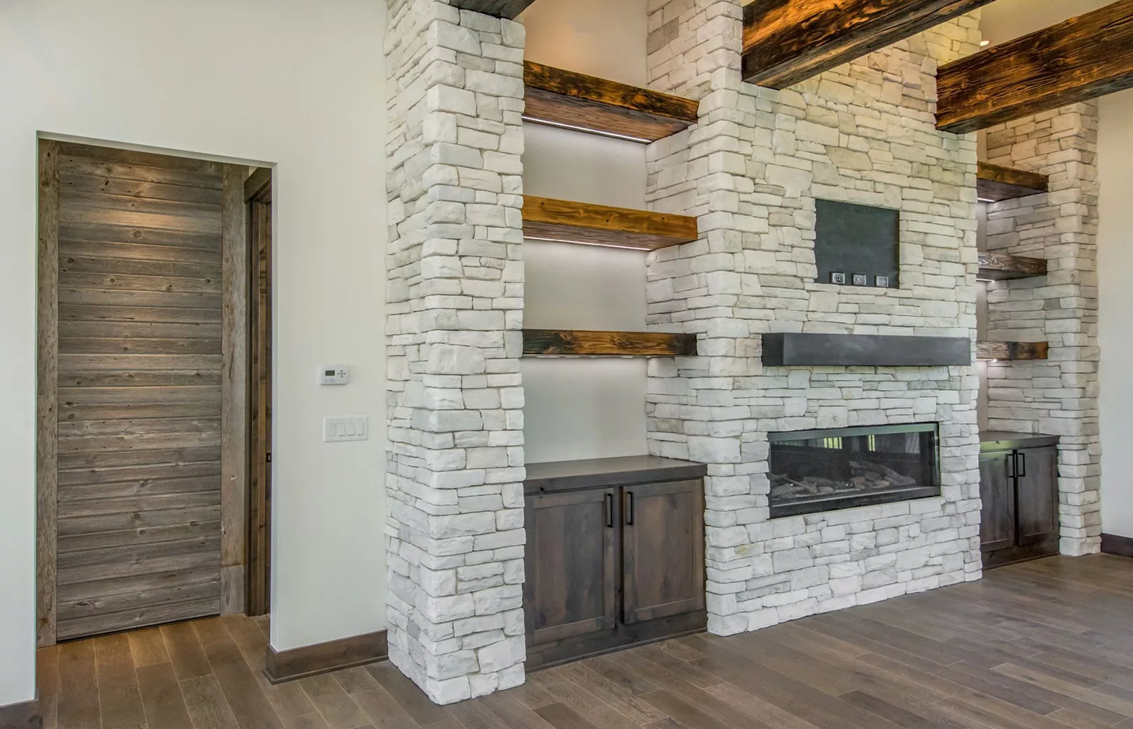 stacked stone pillars, large wooden beam shelving surrounding fireplace