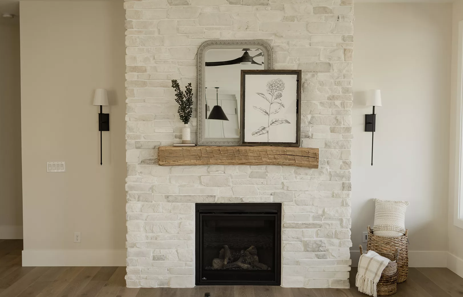 cream walls behind stacked white washed stacked stone fireplace with natural wood beam