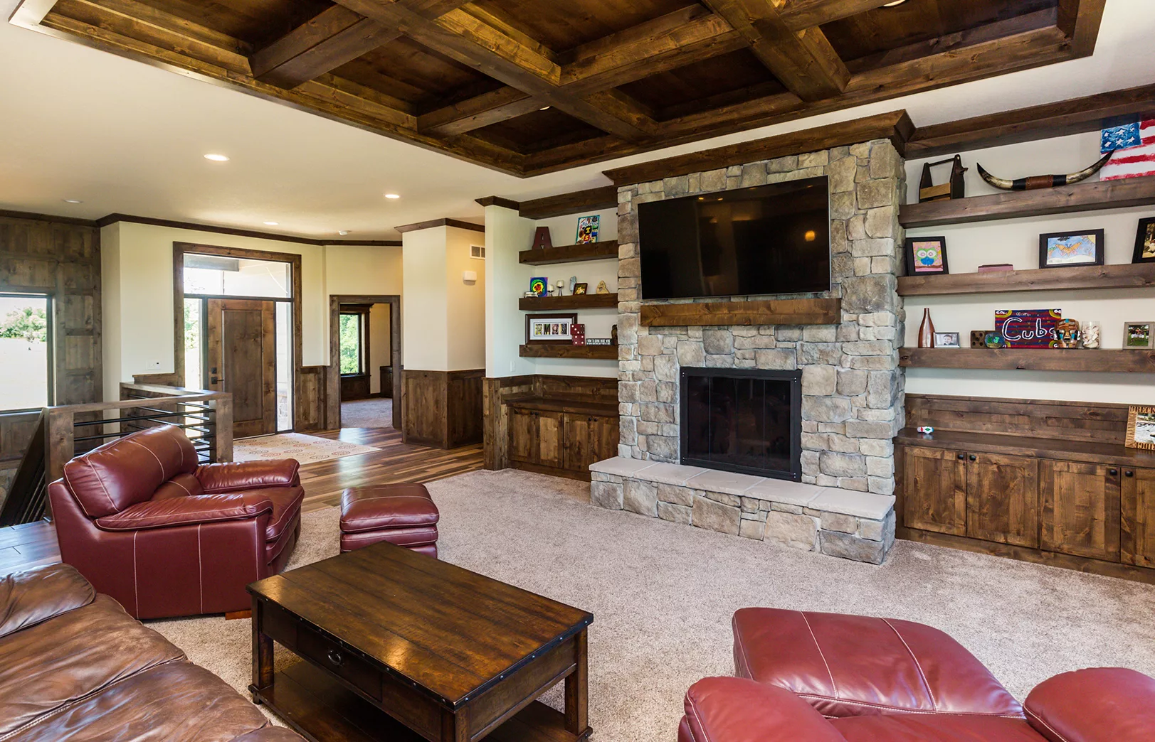 open living area with large stacked stone fireplace and rustic wood cabinets and open floating shelves